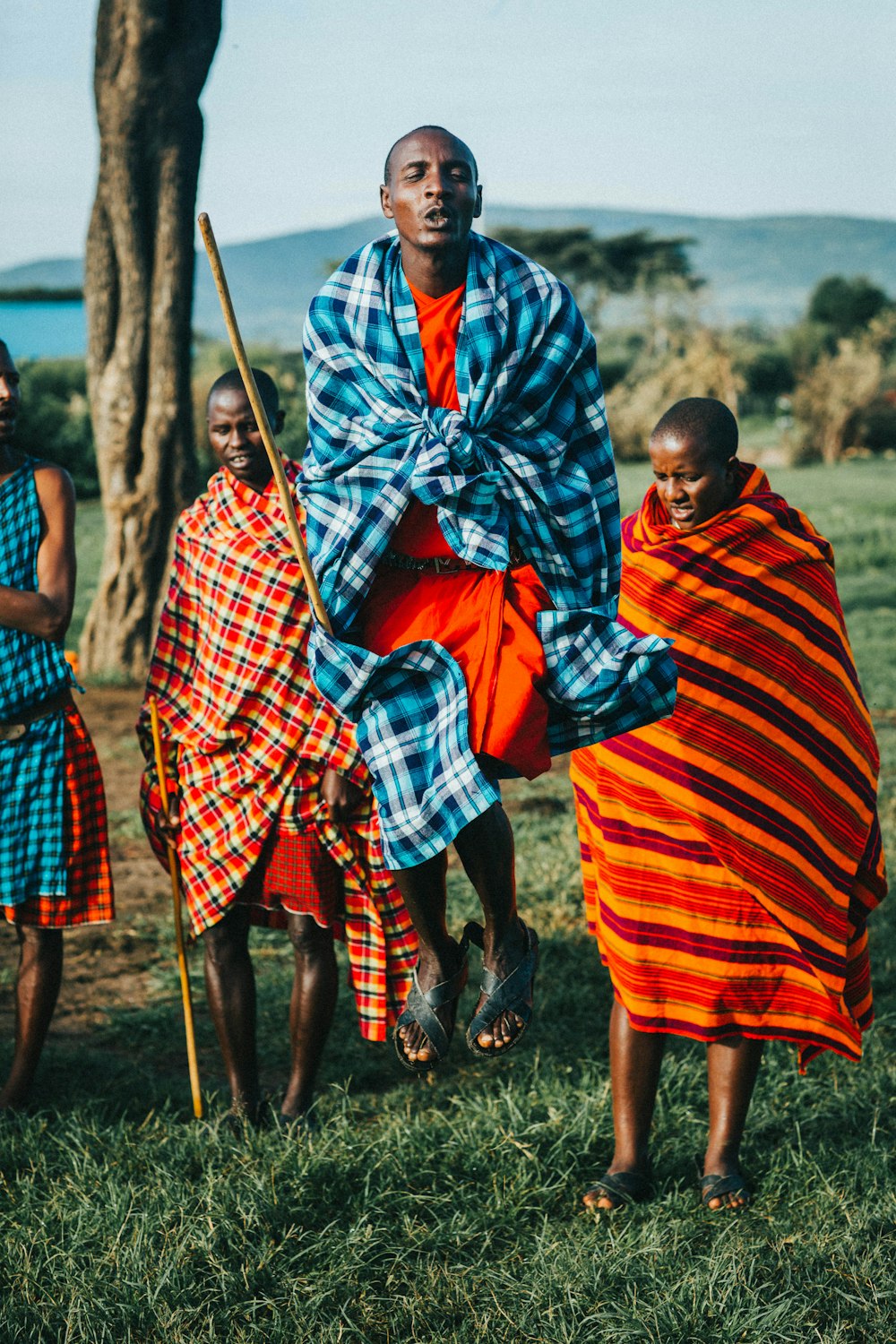 Femme en robe rouge et bleue tenant un bâton marron