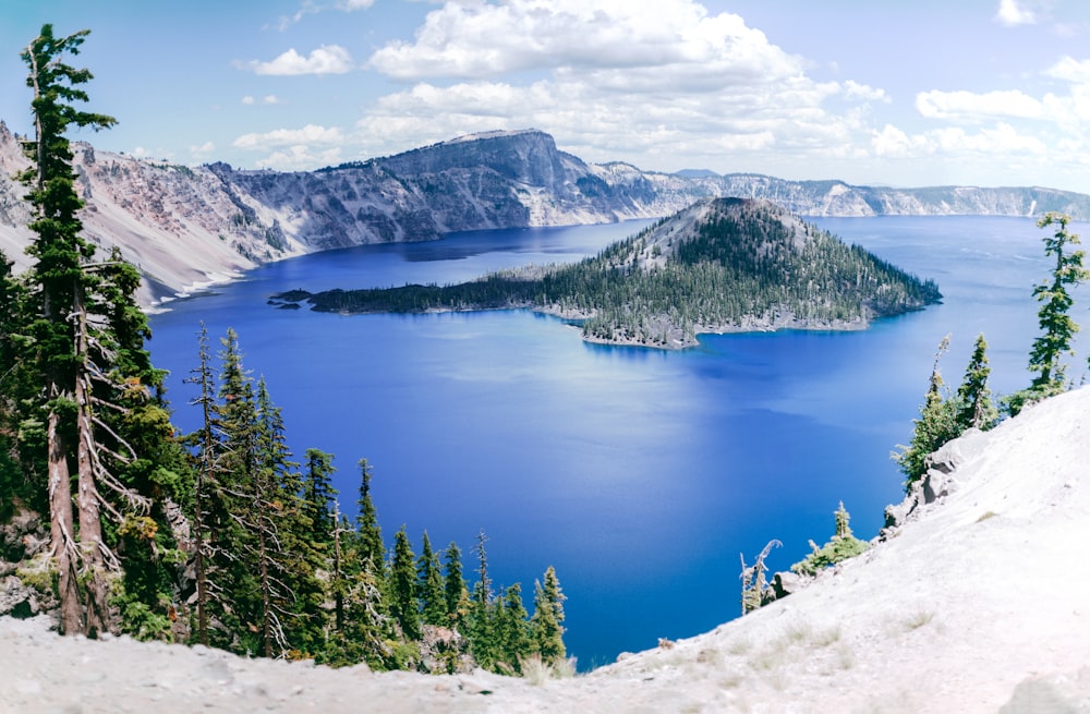 green pine trees on snow covered mountain near lake during daytime