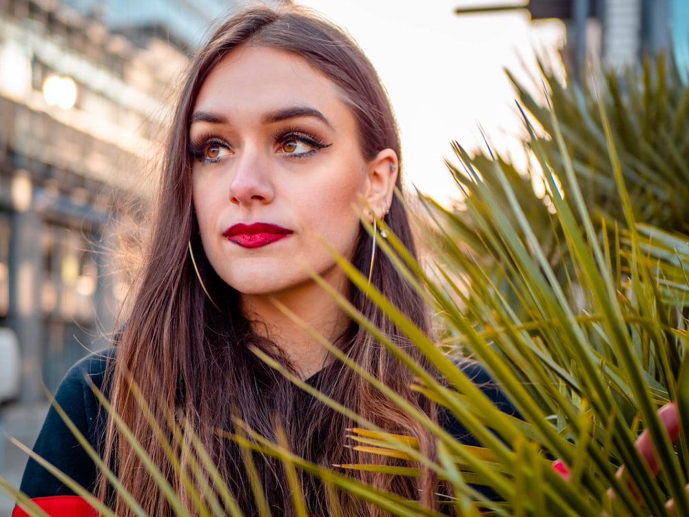 woman in black crew neck shirt standing beside green plant during daytime