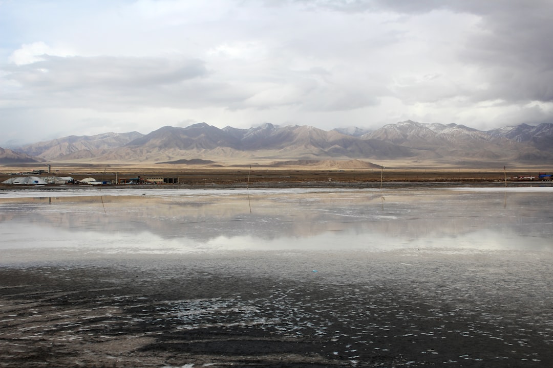 brown field near brown mountains under white clouds during daytime