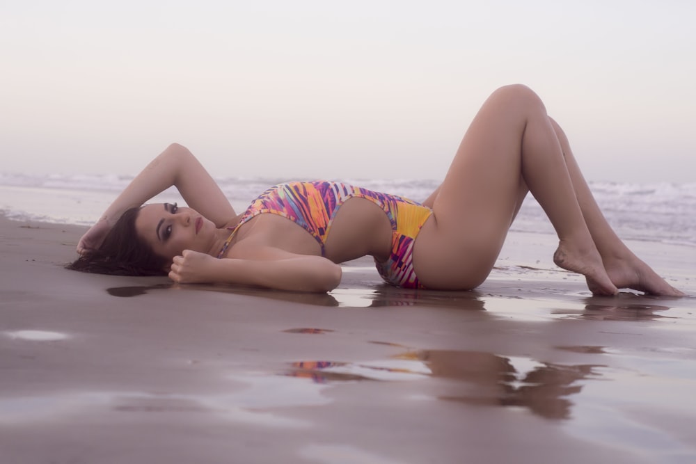 woman in pink and white bikini lying on the beach