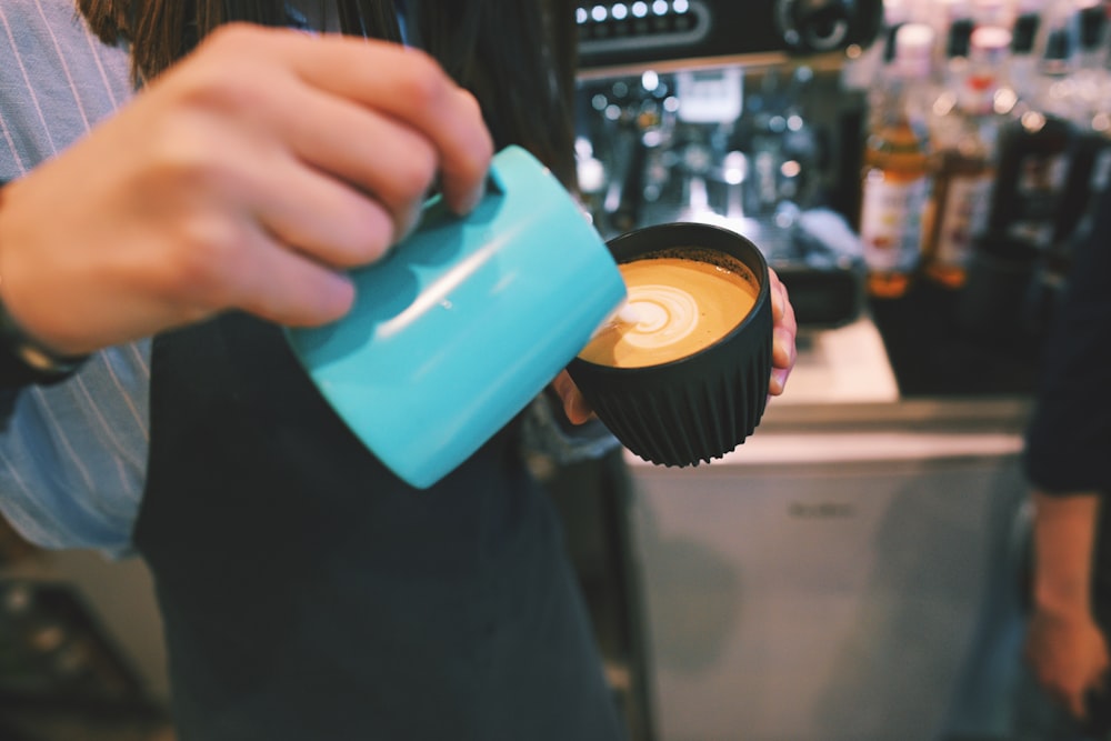 person holding blue ceramic mug with coffee