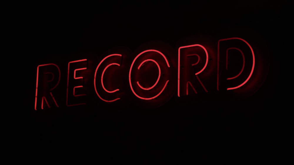 a red record sign lit up in the dark