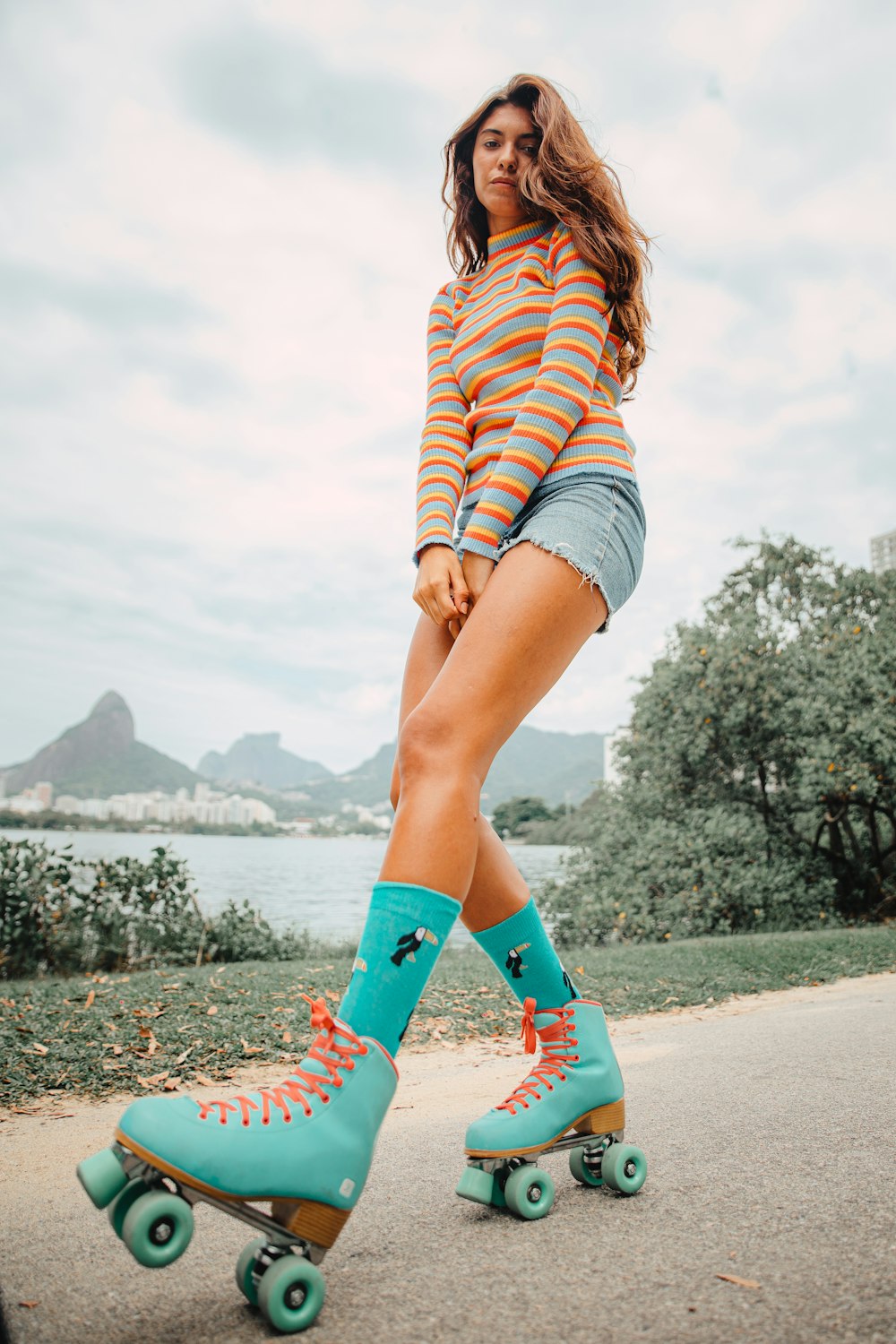 woman in blue white and red striped shirt and blue denim shorts standing on concrete pathway