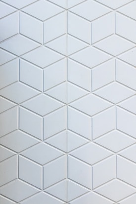 A geometric pattern composed of interlocking hexagonal tiles. Each tile is light gray with a subtle three-dimensional effect, creating an illusion of cubes or stacked diamond-like shapes.