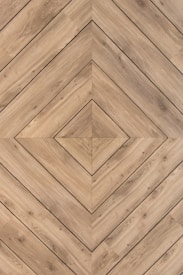 Wooden planks are arranged in a diagonal geometric pattern, forming a symmetrical and visually pleasing design with a central diamond shape. The wood shows natural grain and texture, giving it an organic feel.