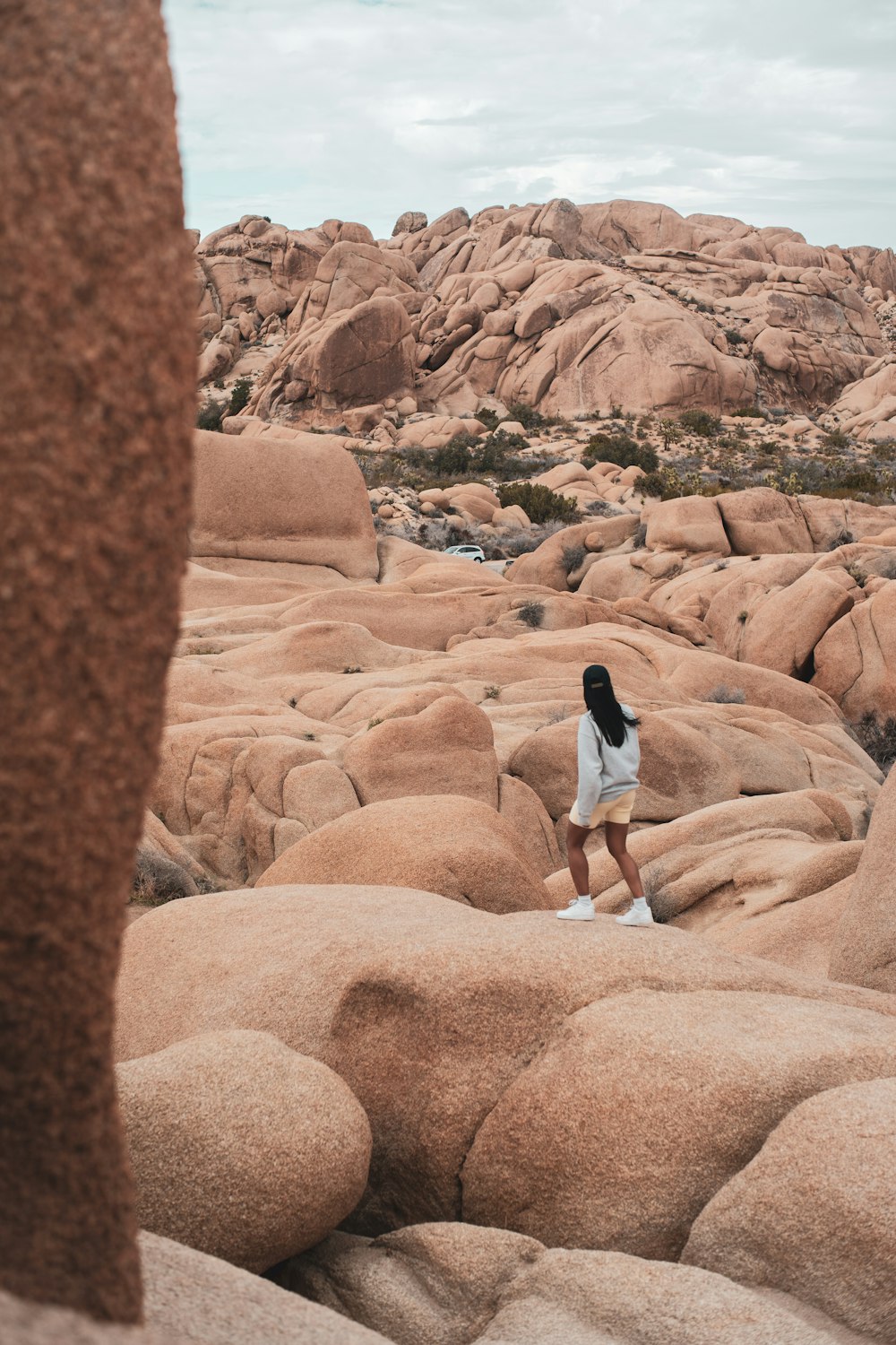 woman in black and white long sleeve dress walking on brown rock formation during daytime