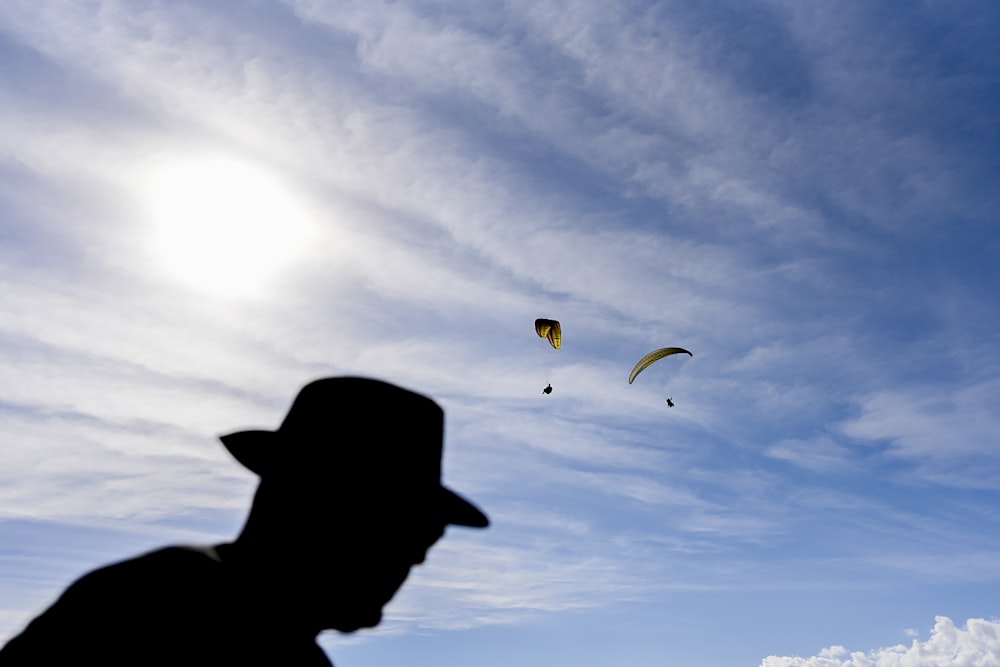 silhouette of person with parachute in mid air during daytime