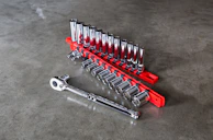 Close-up of a red fire-colored wrench resting on a clean gray workbench.
