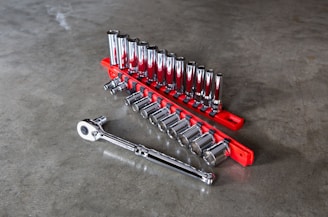 A sleek metallic gray motorcycle tool set arranged neatly on a red background.