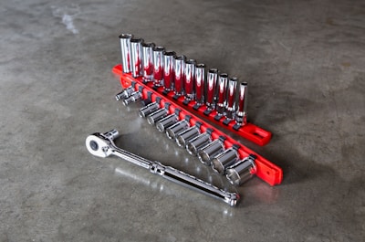 A sleek metallic gray motorcycle tool set arranged neatly on a red background.