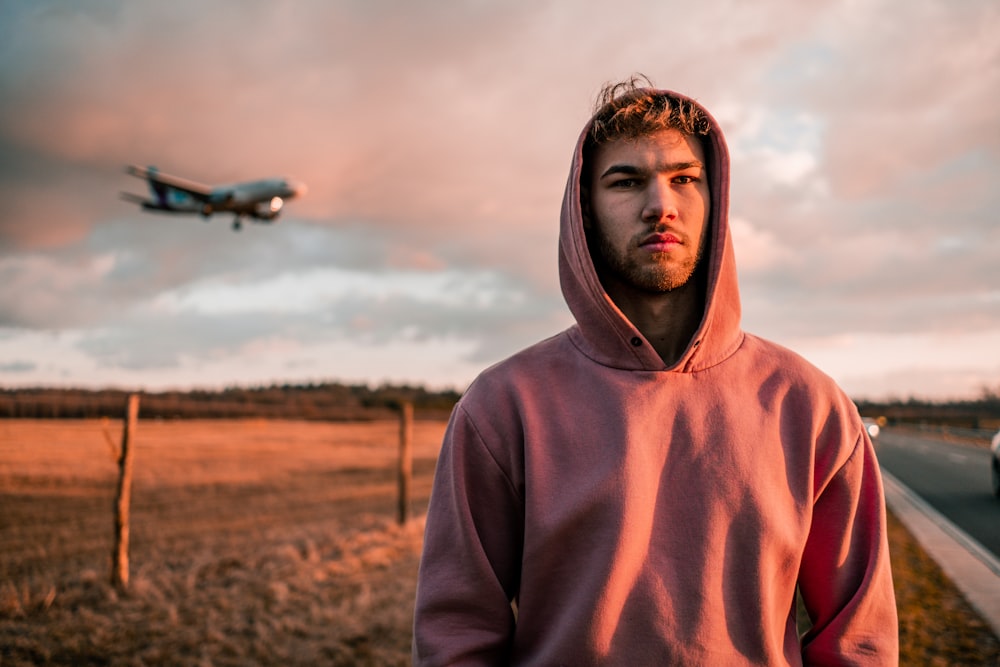 man in brown hoodie standing on brown field during daytime