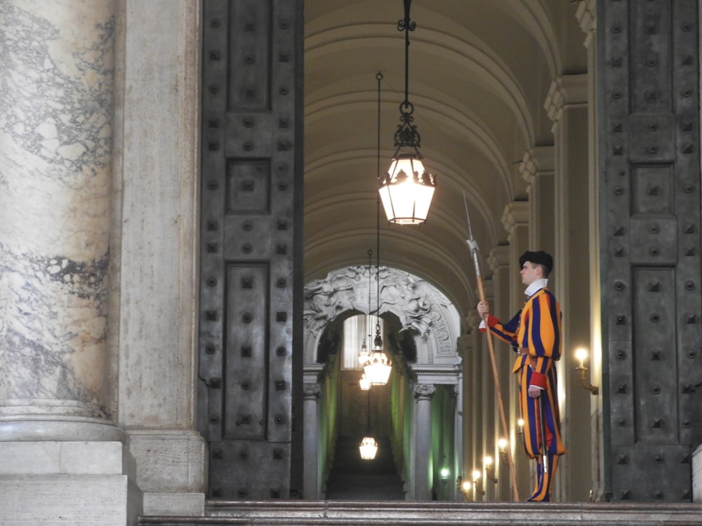 man in red and white robe standing on hallway