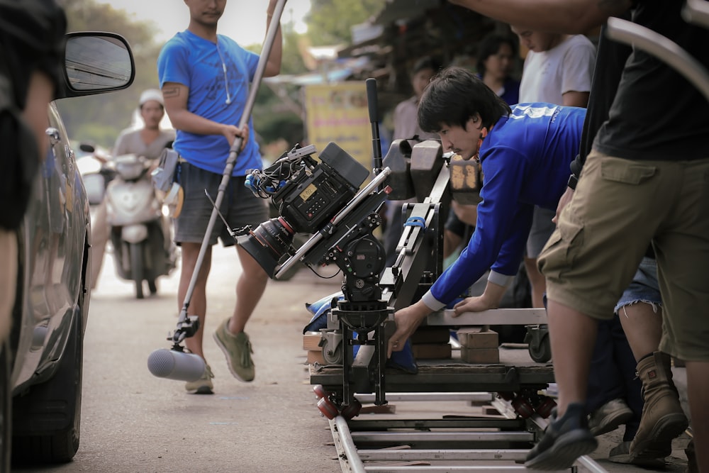 man in blue shirt and brown pants holding black dslr camera