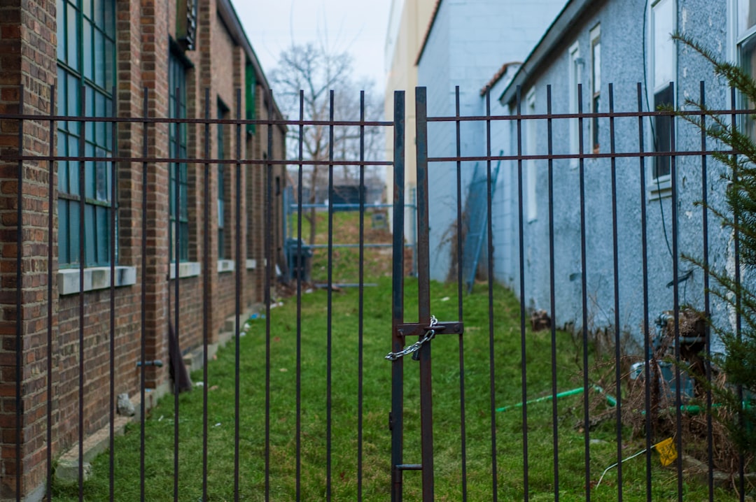 grey metal fence near brown wooden house during daytime