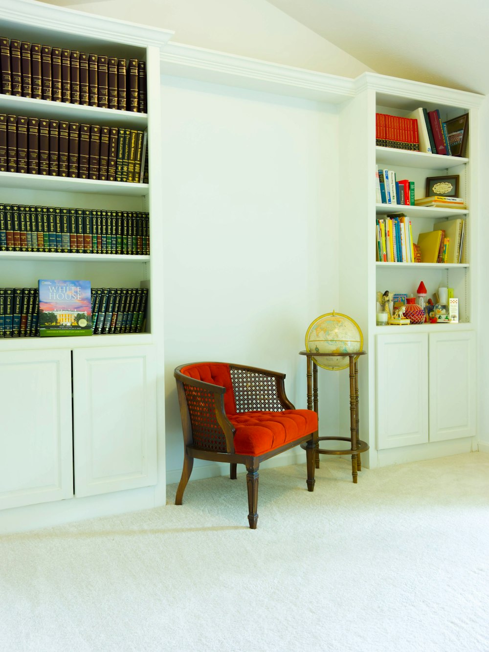 red padded brown wooden armchair beside white wooden shelf