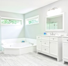 white ceramic bathtub near white wooden vanity sink
