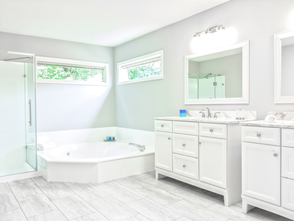 white ceramic bathtub near white wooden vanity sink