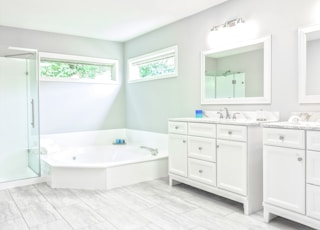 white ceramic bathtub near white wooden vanity sink