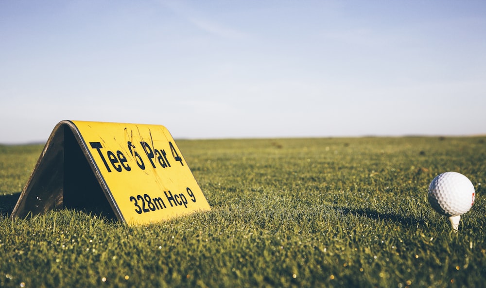 Panneau d’avertissement jaune et noir sur un terrain en herbe verte