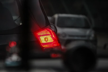 Close-up of a breathalyzer device with a blurred police car in the background.