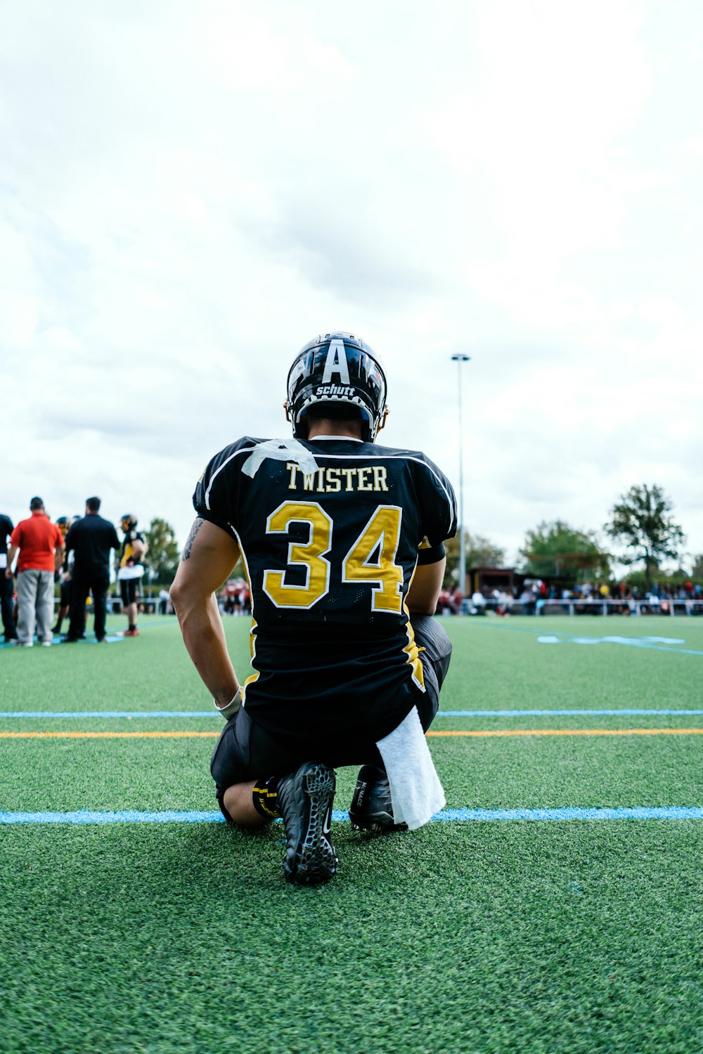 football players in black and yellow jersey shirt and black pants running on field during daytime