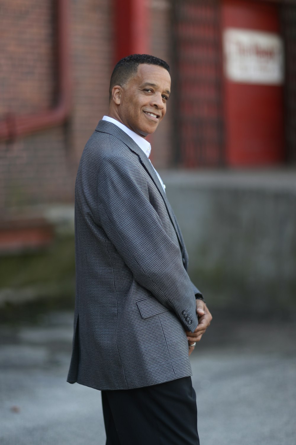 man in gray suit jacket standing on road during daytime