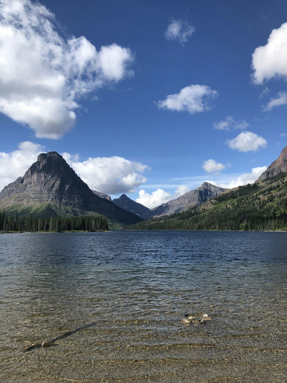 lake near green mountain under blue sky during daytime