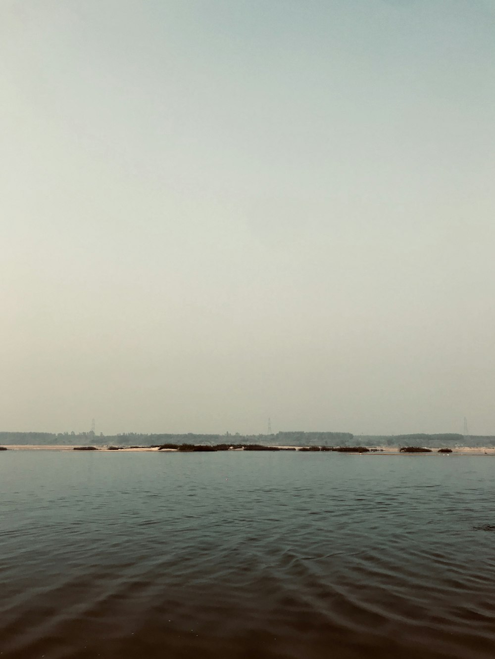 body of water under white sky during daytime