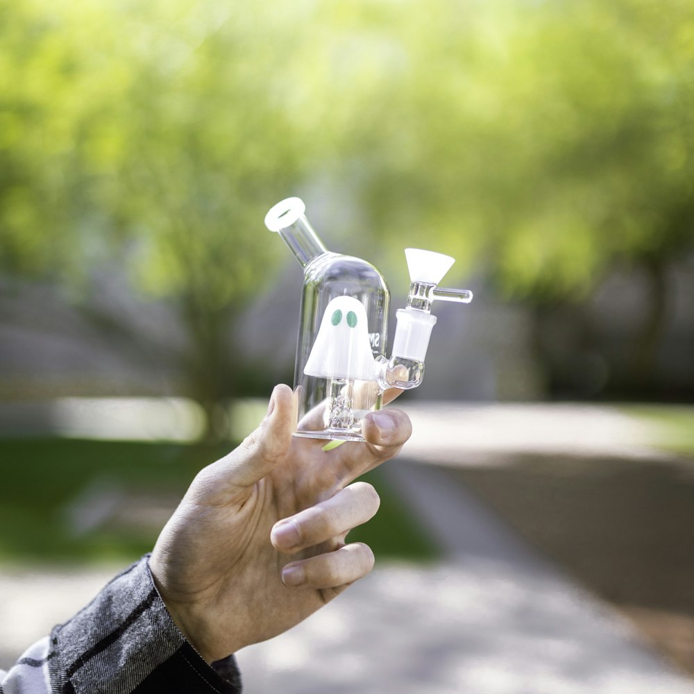 personne tenant une bouteille en verre transparent