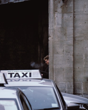 man in black jacket standing beside car during daytime