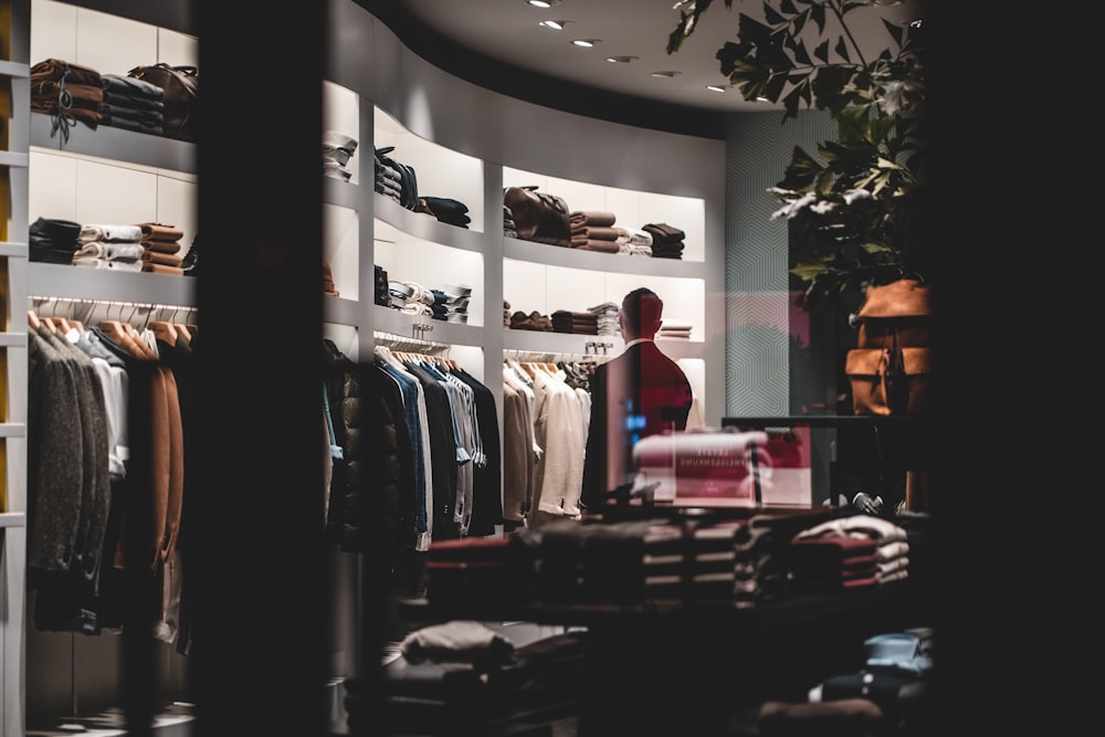 woman in red shirt standing near clothes rack