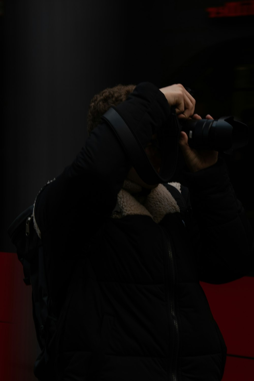 黒いデジタル一眼レフカメラを持つ黒いジャケットの男