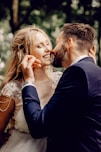 man in black suit kissing woman in white floral dress