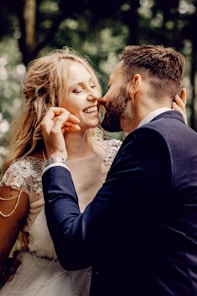 man in black suit kissing woman in white floral dress