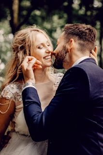 man in black suit kissing woman in white floral dress