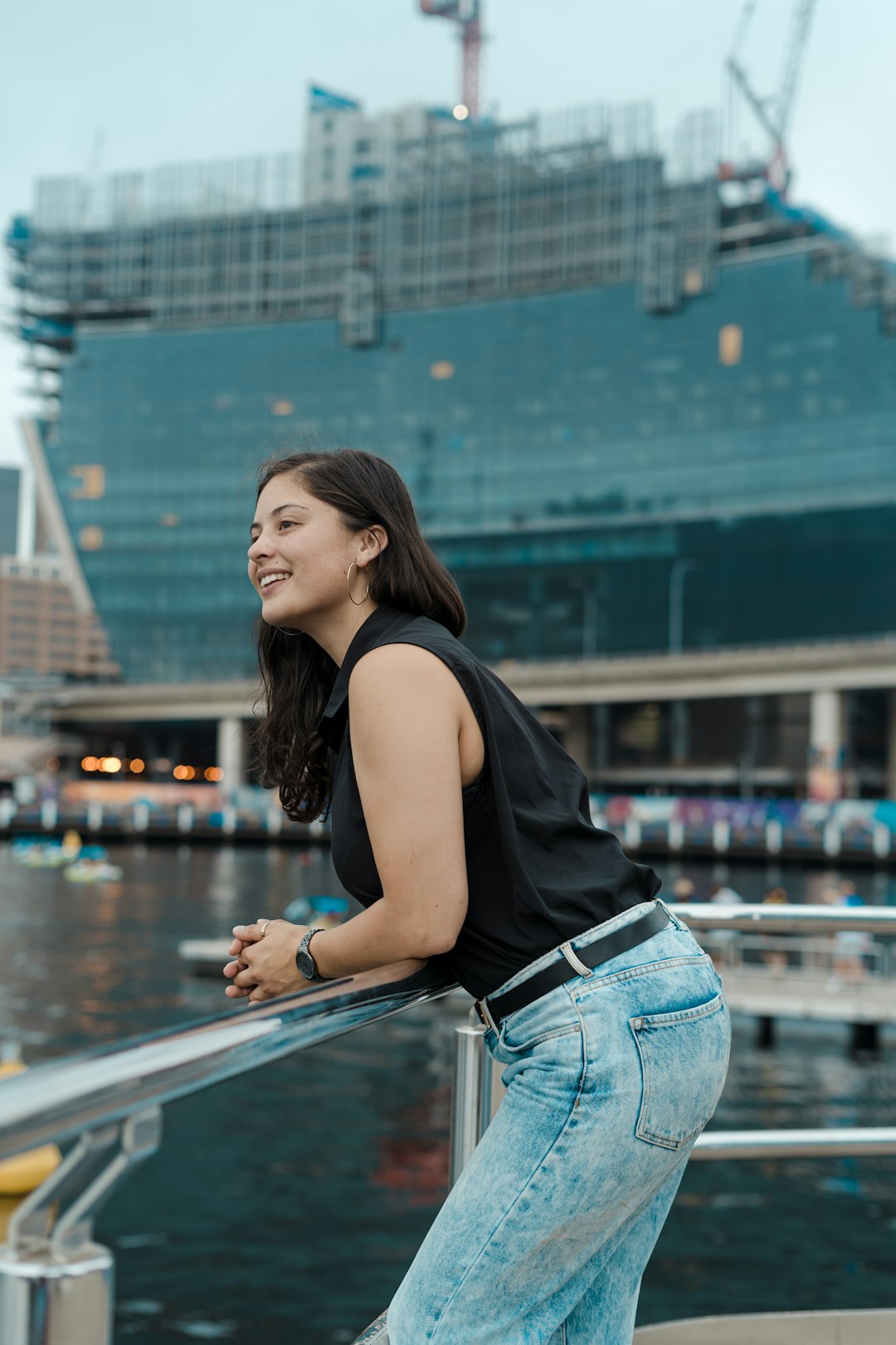 woman in black tank top and blue denim jeans leaning on railings