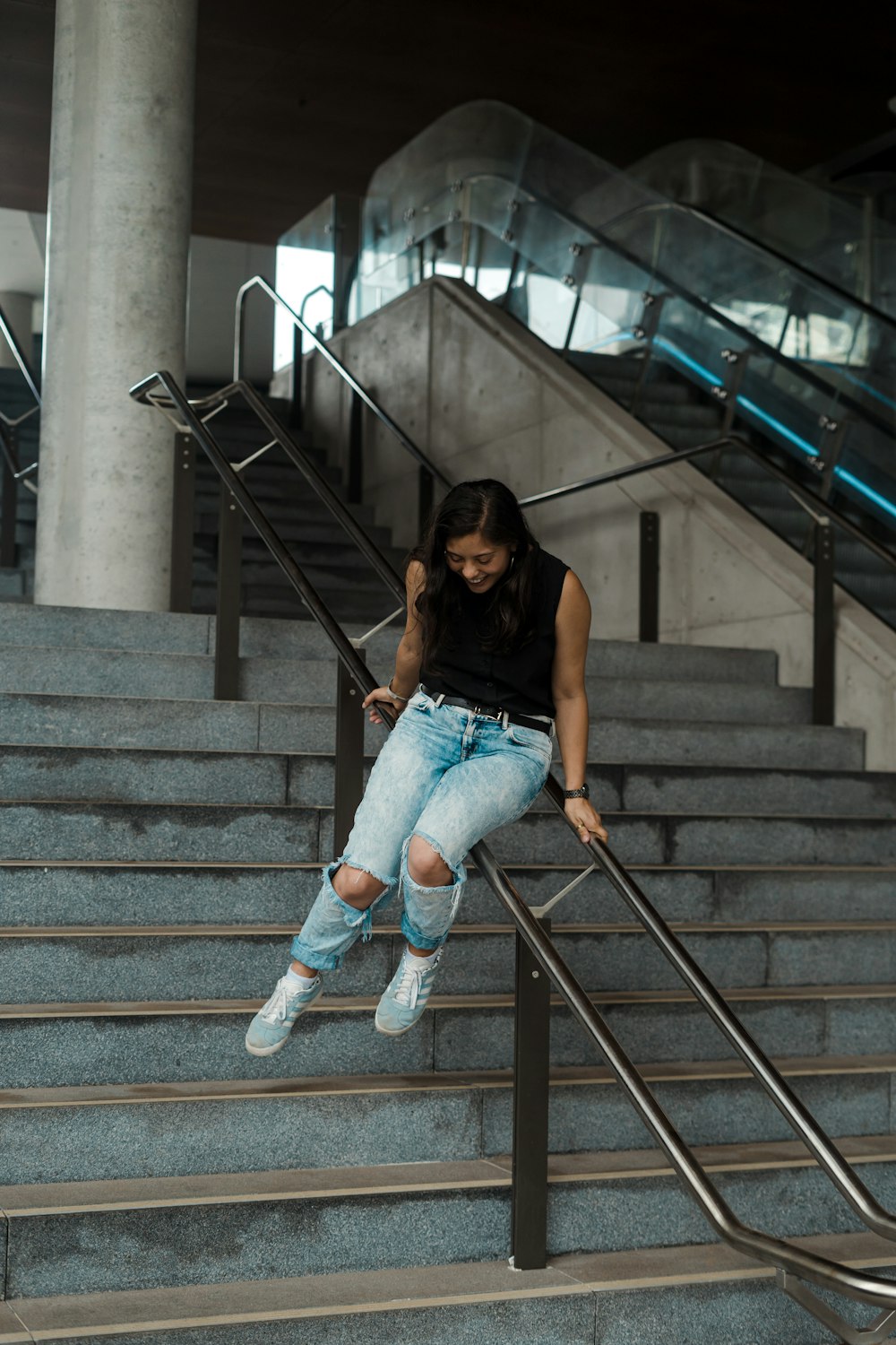 a woman sitting on a stair rail next to a set of stairs