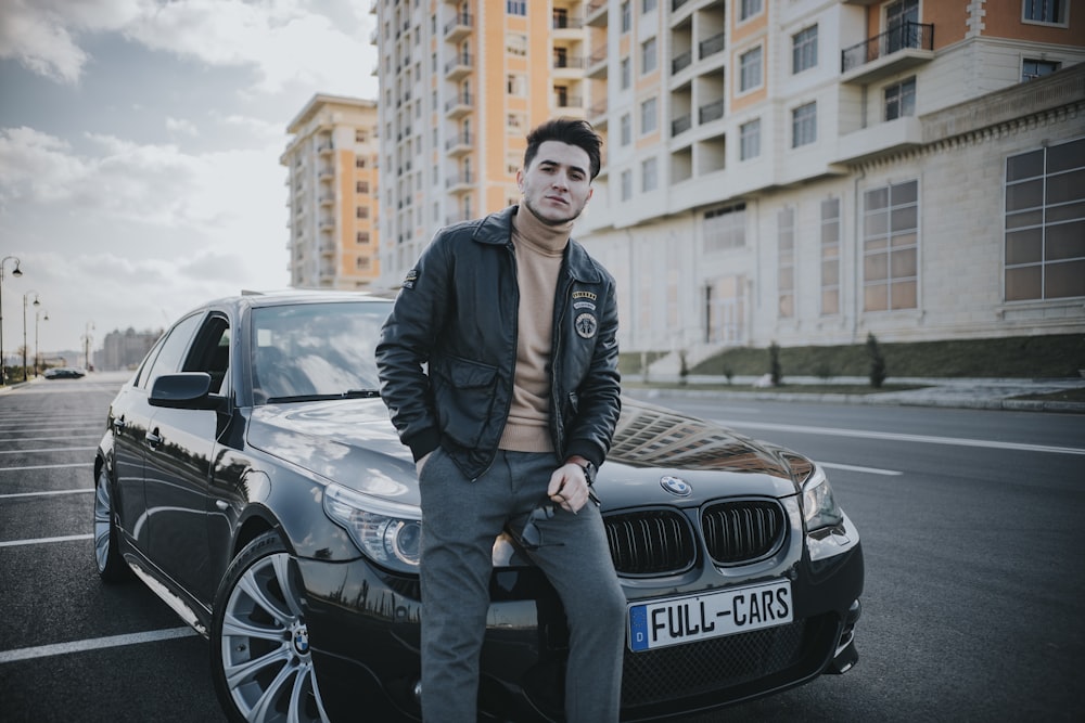 man in black jacket standing beside black mercedes benz car