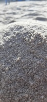 Close-up of a sand-resistant mat partially covered in sand on a beach setting.