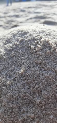 Close-up of a sand-resistant mat partially covered in sand on a beach setting.