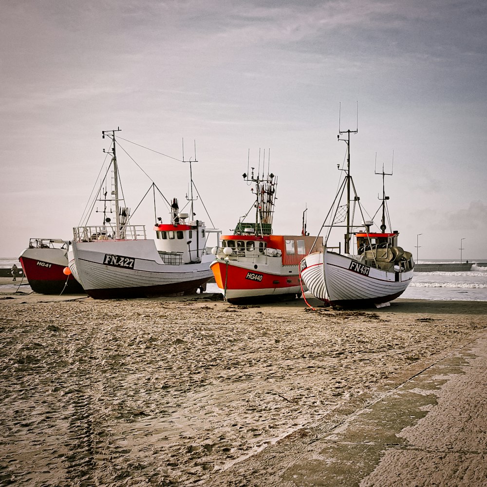 Barco blanco y rojo en la orilla del mar durante el día