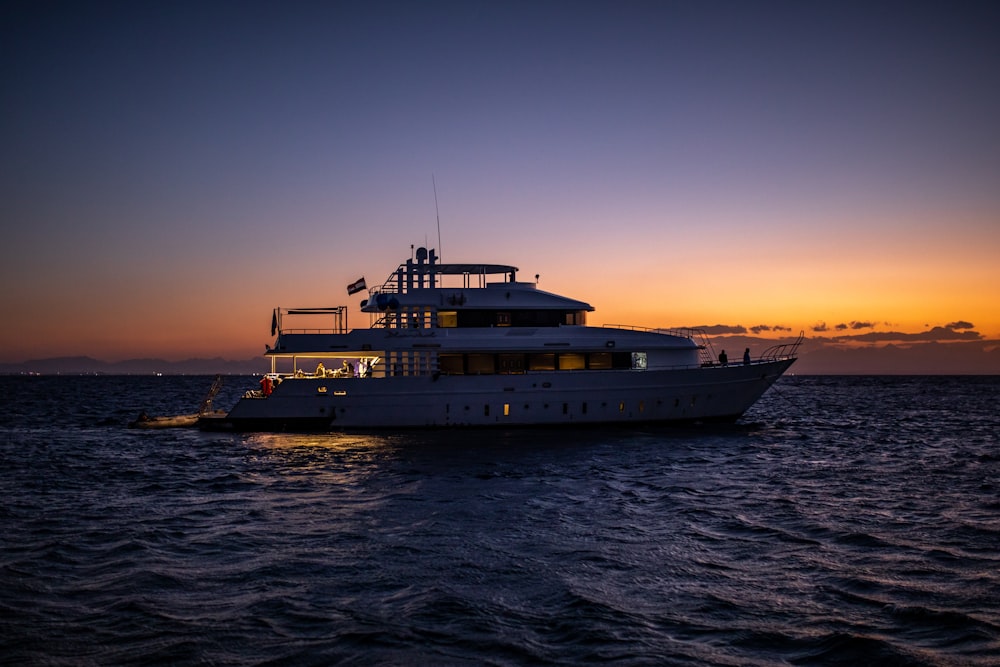 white ship on sea during sunset