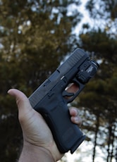 person holding black semi automatic pistol