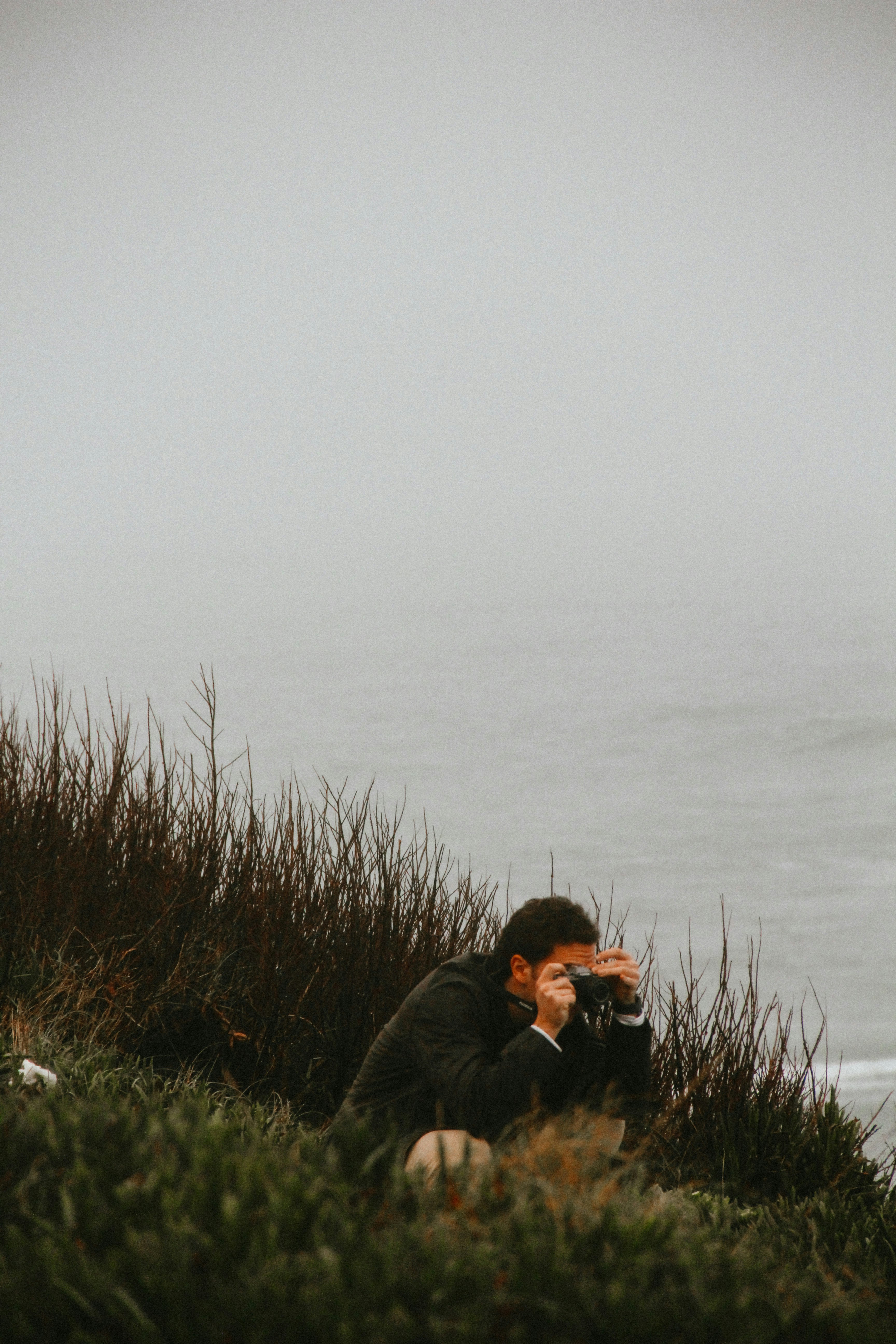 man in black jacket taking photo of sea