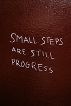 A motivational quote on a blackboard with green chalk, encouraging steady progress.