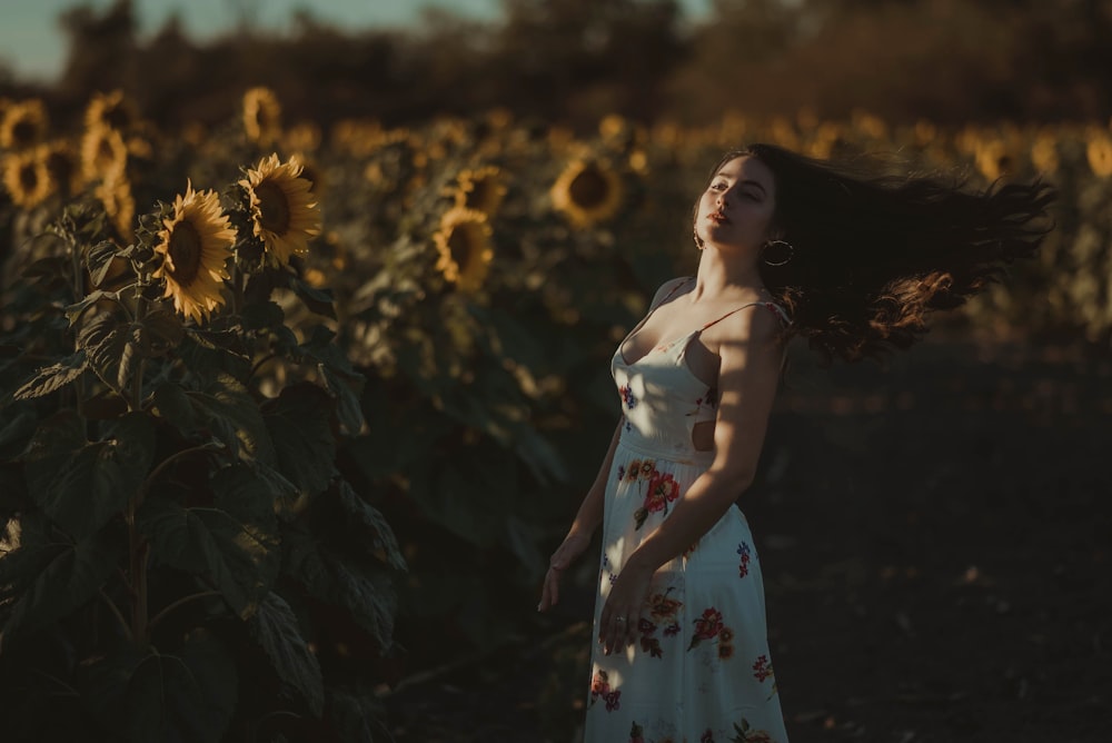 woman in white and red floral dress standing on sunflower field during daytime