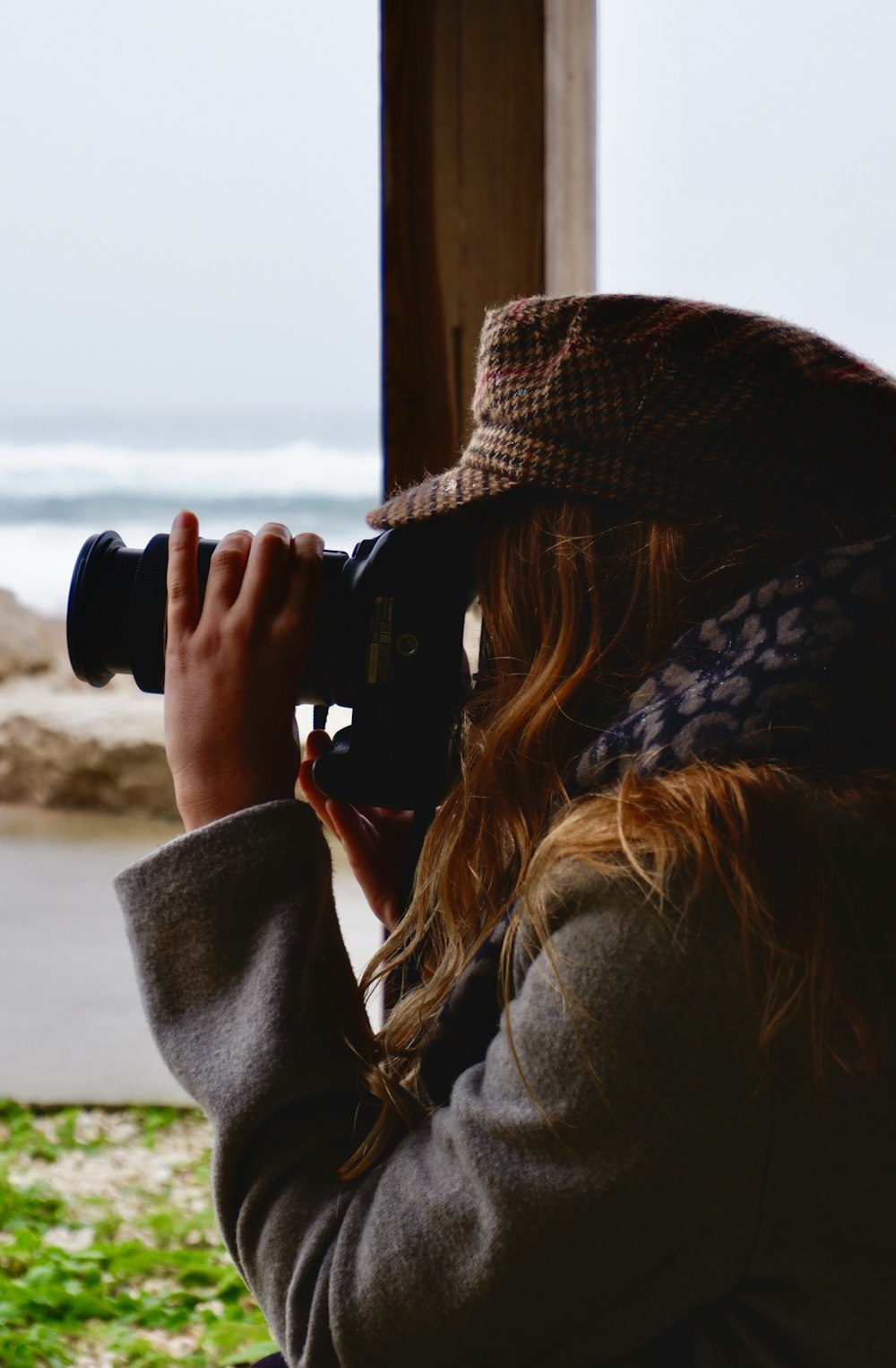 woman in gray coat using black dslr camera during daytime