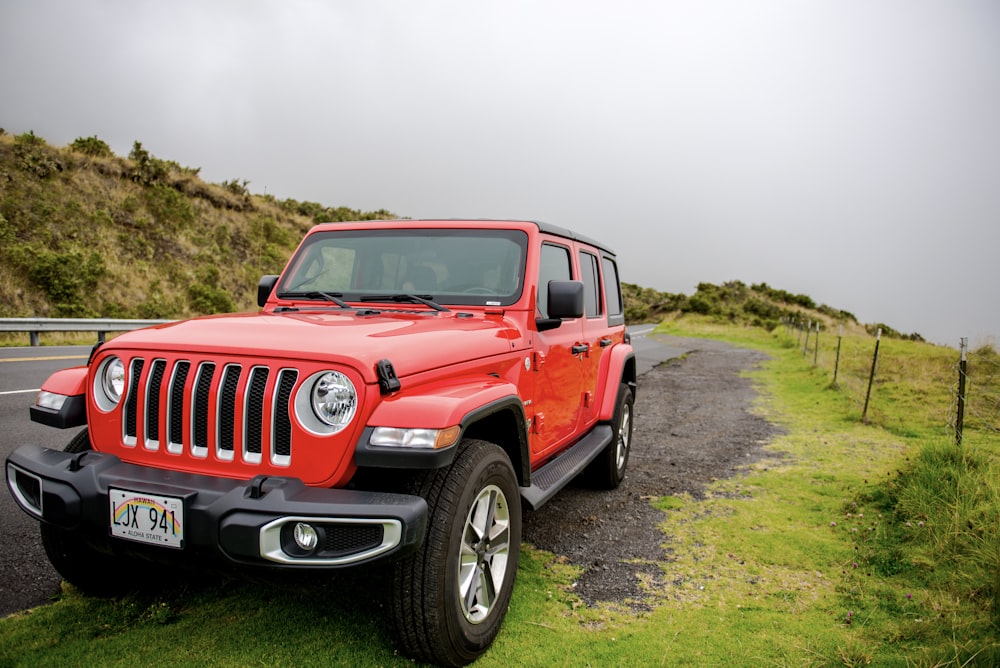 red jeep wrangler on green grass field during daytime