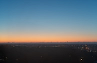 Evening view of solar panels with city lights beginning to twinkle in the background.